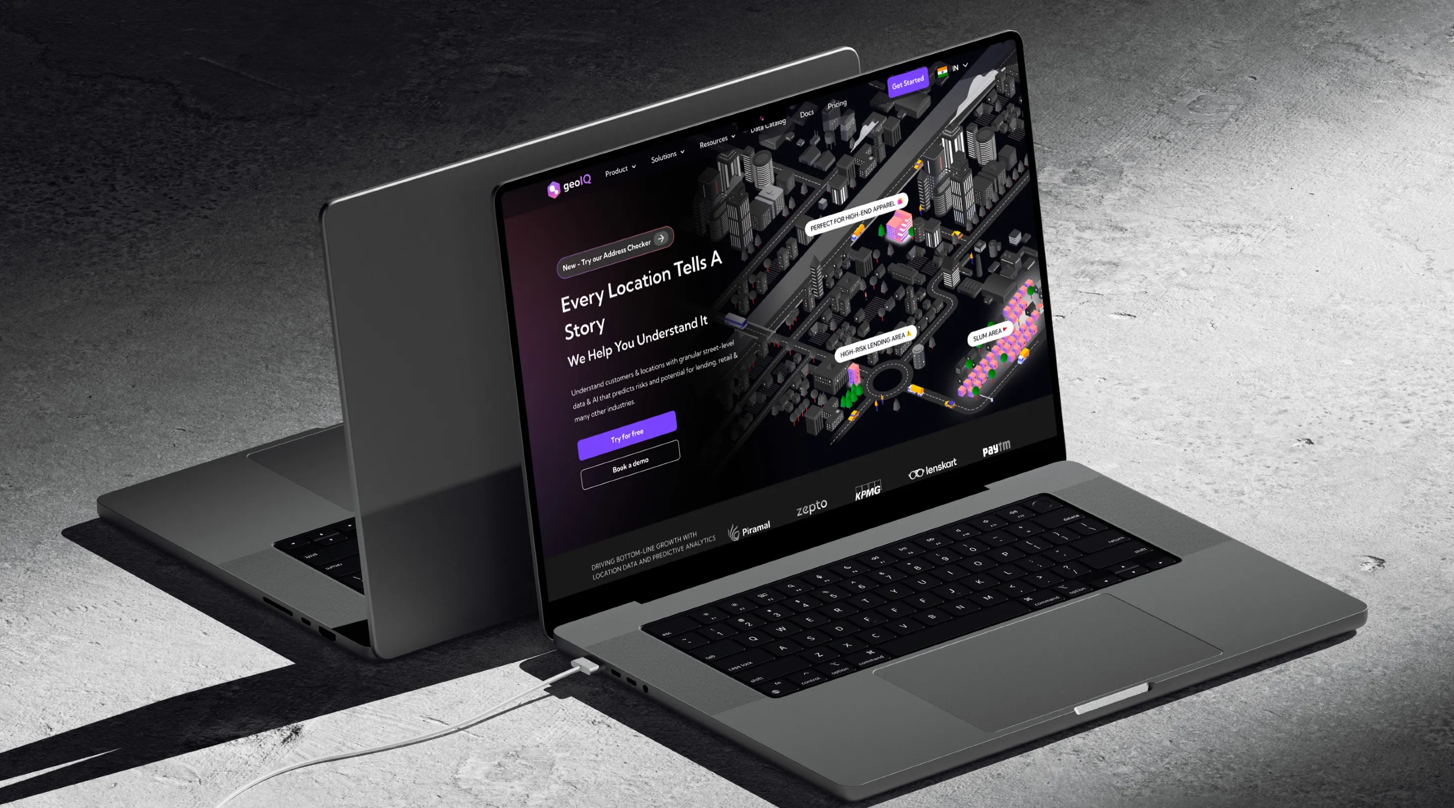 GeoIQ's rebranded website, 'Every location tells a story', on two laptops in a dark studio setting.